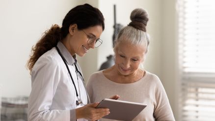Eine Ärztin zeigt ihrer älteren Patientin etwas auf einem Tablet
