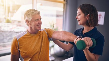 Eine Physiotherapeutin trainiert die Schulter eines Patienten