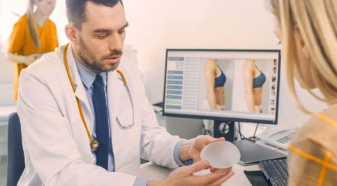 Ein Arzt zeigt einer Patientin ein Brustimplantat