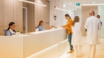 Empfangsbereich einer Praxis mit medizinischem Personal, Patientin und Ärzten