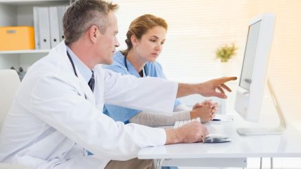 Ein Arzt und eine medizinische Fachangestellte interpretieren einen Befund auf einem Computer