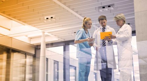 Ein Arzt, eine Ärztin und eine Pflegerin beraten sich in einem Krankenhaus